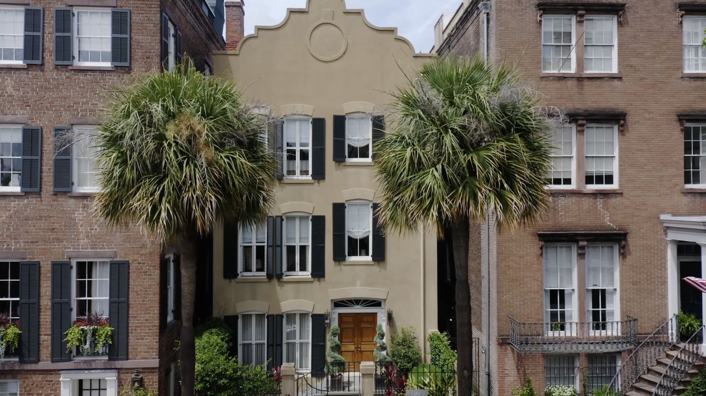 A historic stucco townhouse behind a curved parapet gable in downtown Savannah