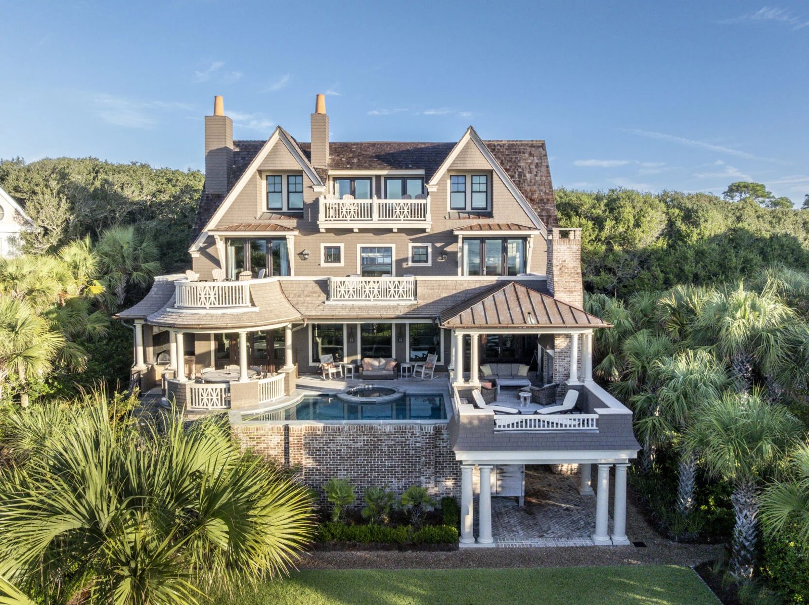 Aerial view of a red-cedar-shingled house on Kiawah Island from the rear, with a pool, covered porches and palmettos