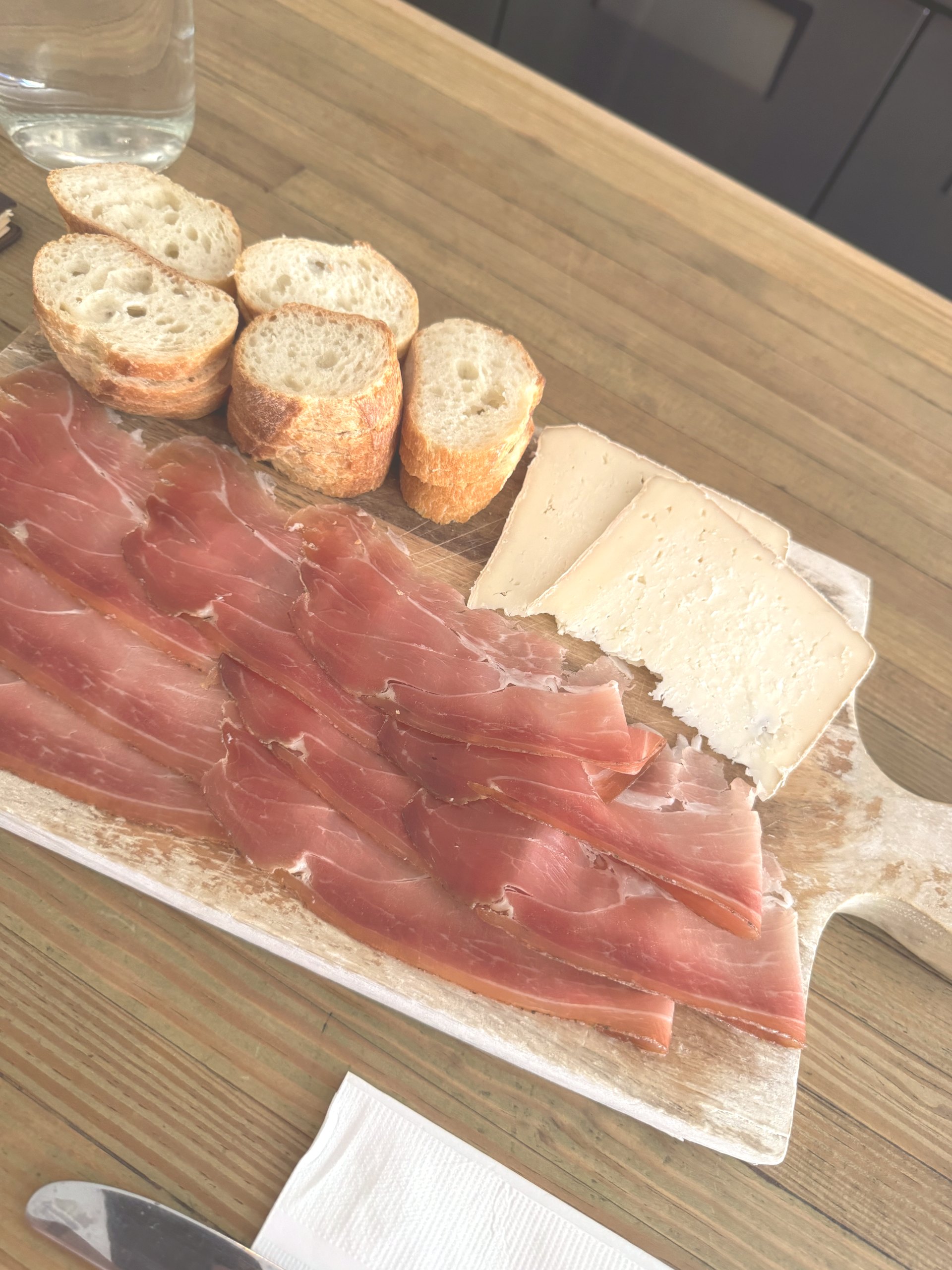 A wooden board of sliced bread, cured meat and cheese at Sorelle in Charleston in the late afternoon