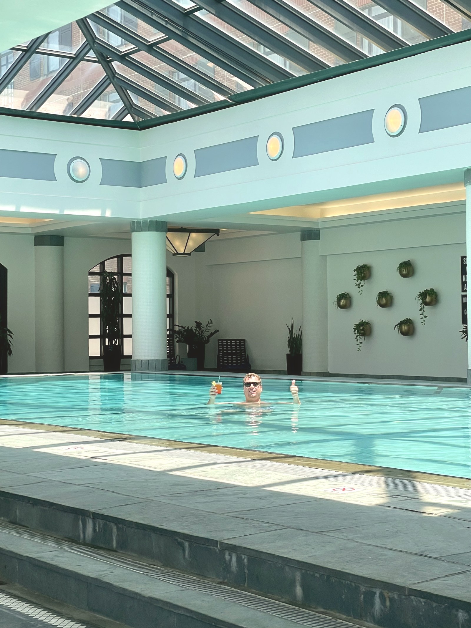 Damian Hall in the glass roofed pool at Charleston Place in June 2022, holding a cocktail, before the pool deck rebuild