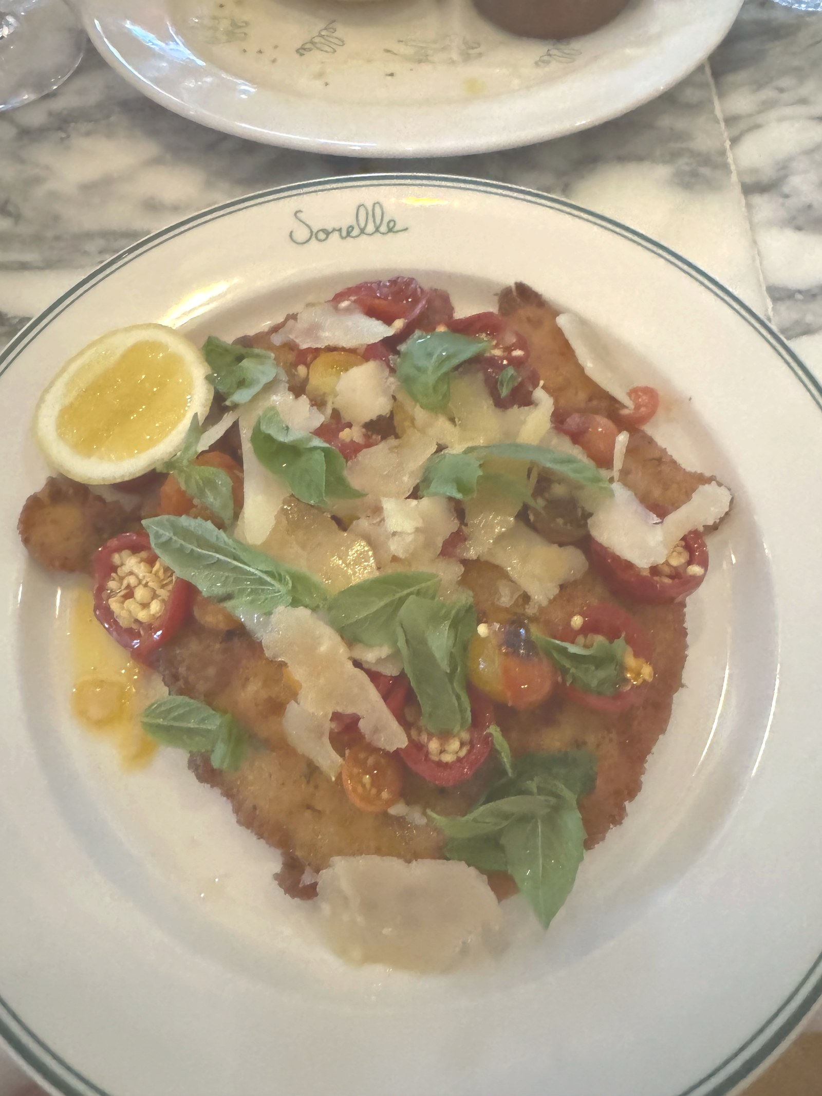 Chicken Milanese at Sorelle in Charleston, a parmesan crusted cutlet under blistered tomatoes, basil and shaved Vacche Rosse with half a lemon