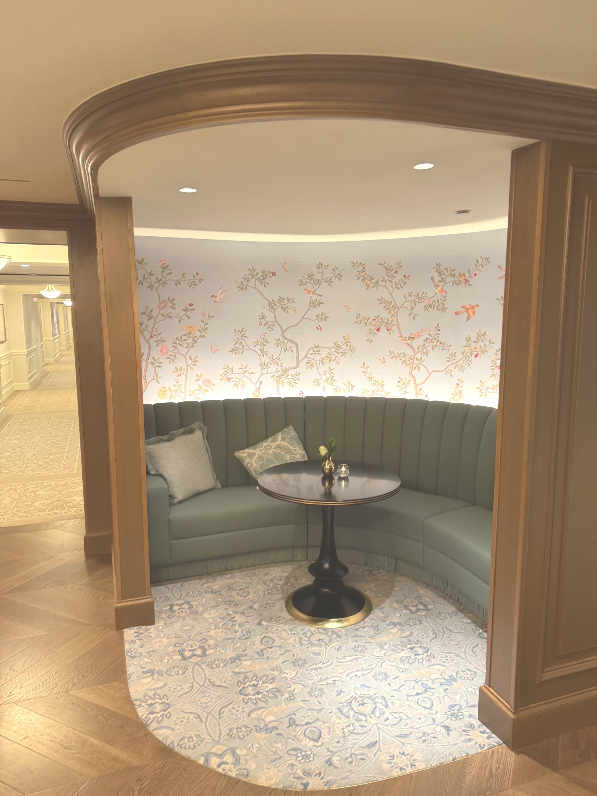 A curved green banquette in an arched alcove with hand painted wallpaper on the renovated Club Level at The Charleston Place