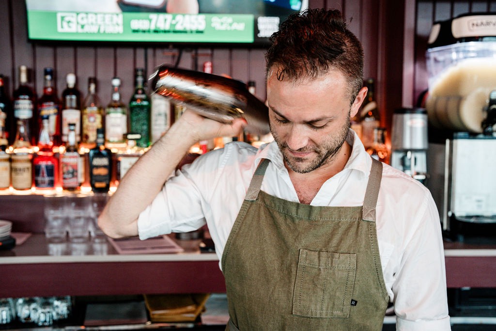 A bartender shaking a cocktail behind the bar at Lou Lou's Tavern on the Tracks