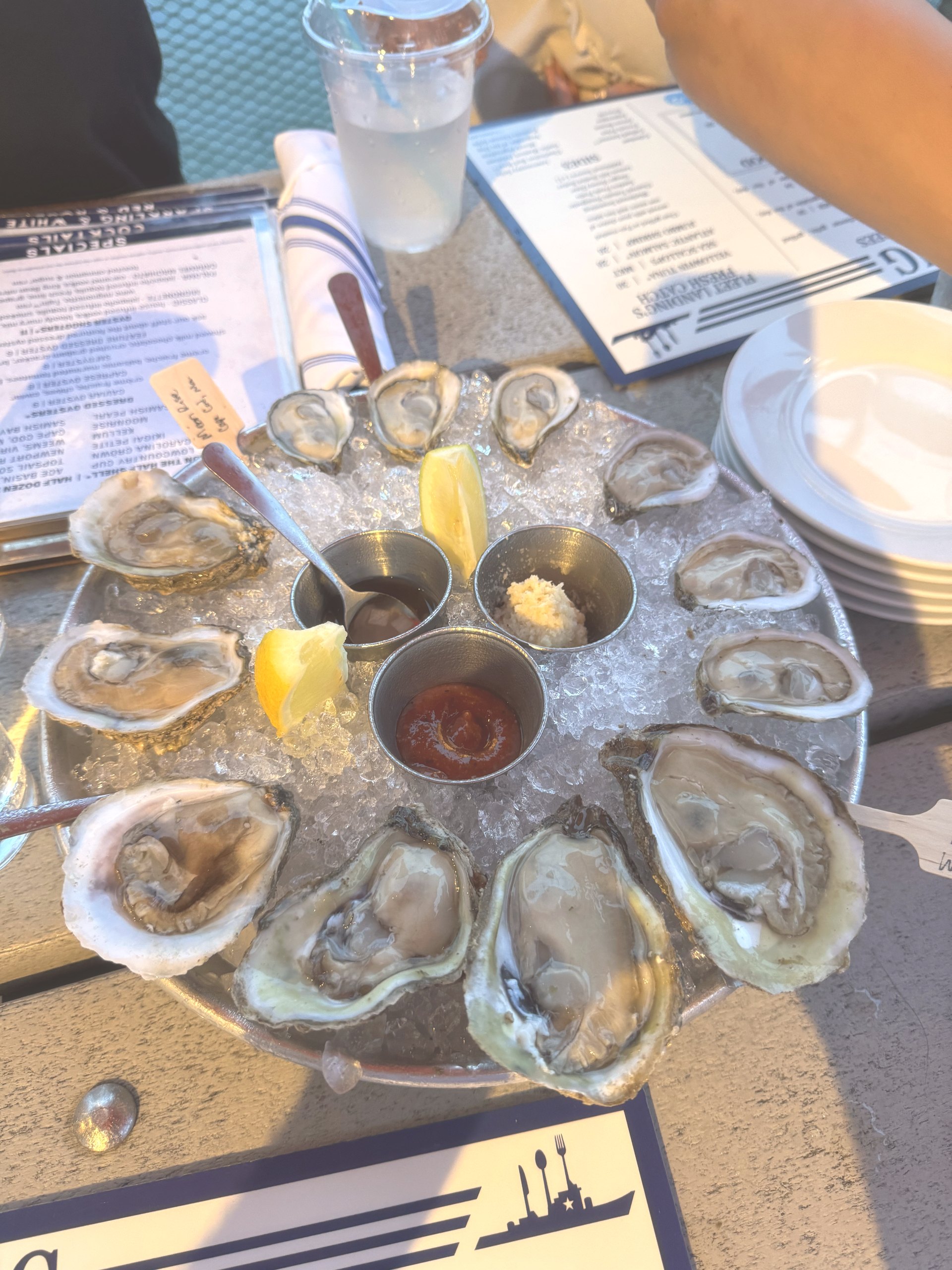 A dozen oysters on ice with lemon and sauces on a Charleston harbor placemat at Fleet Landing