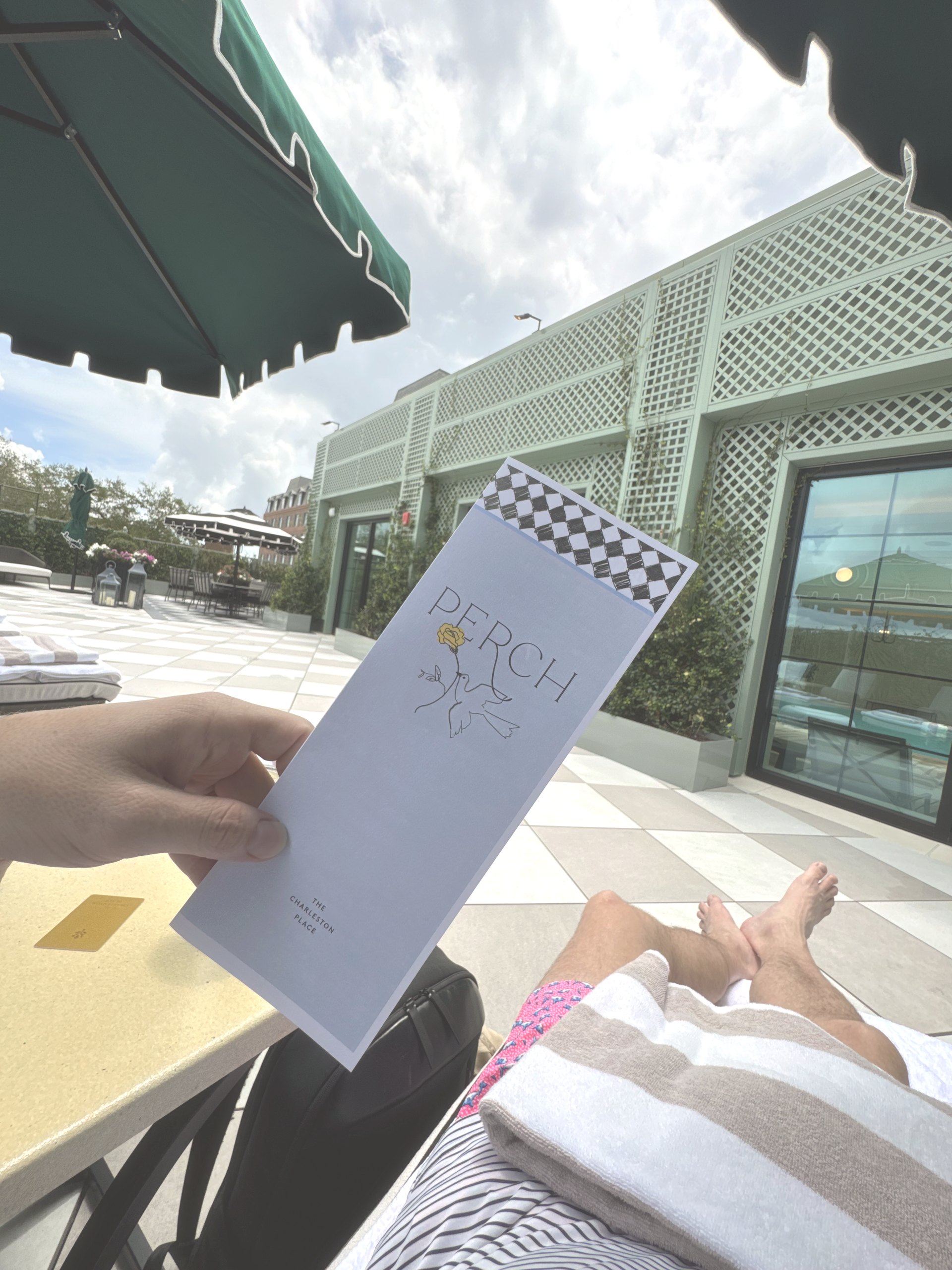 The Perch menu held over a lounger beside the pool deck at The Charleston Place