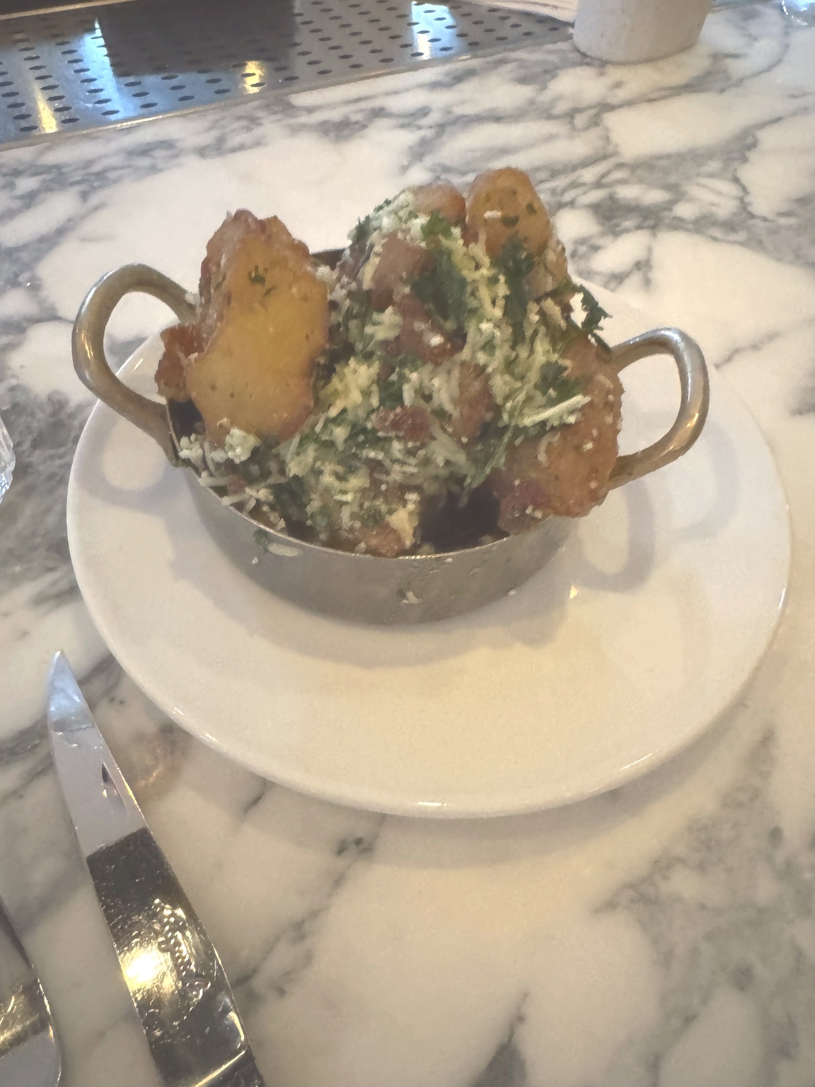 Patates, olive oil fried potatoes with rosemary and Castelmagno, in a copper pot on marble at Sorelle in Charleston