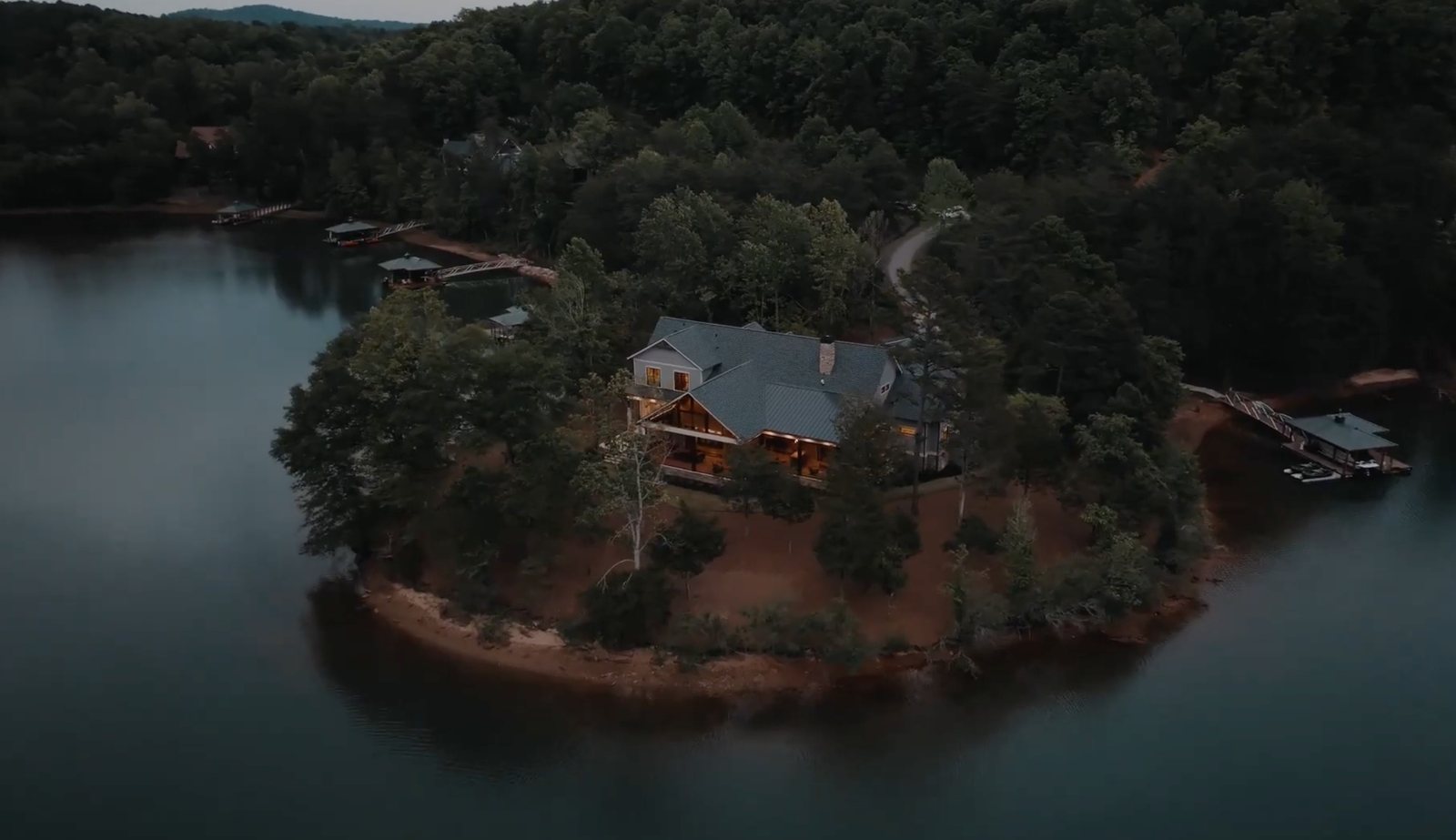 The house at dusk on its own peninsula in a quiet cove of Lake Keowee, with the dock to the right