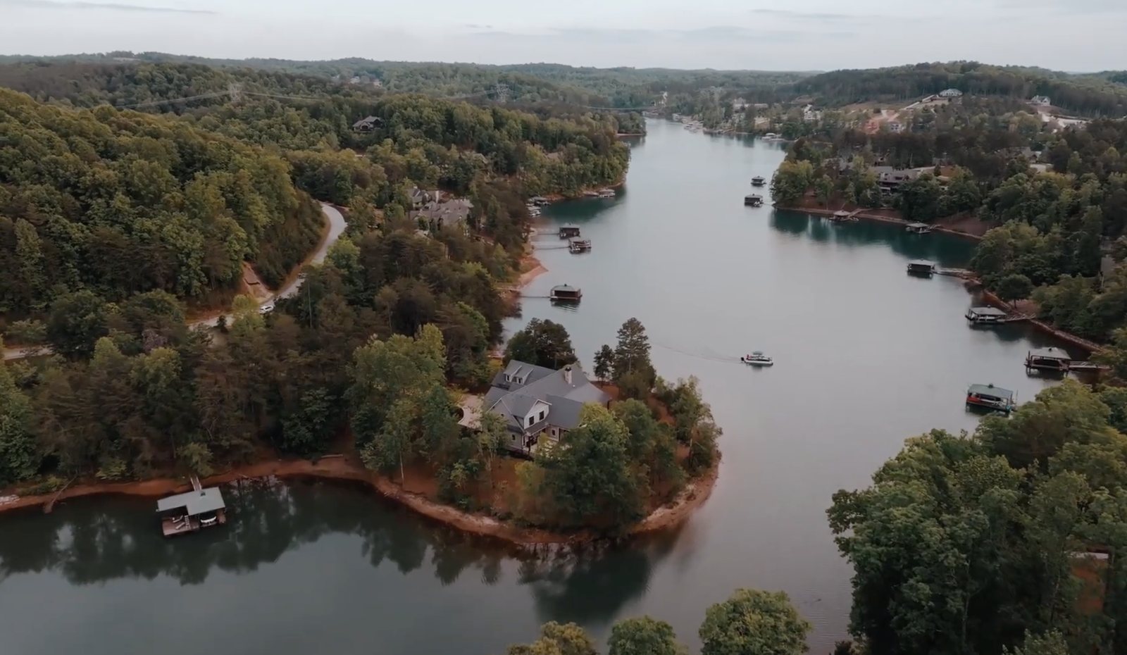Aerial looking down the lake, the house on its point with boats running the main channel