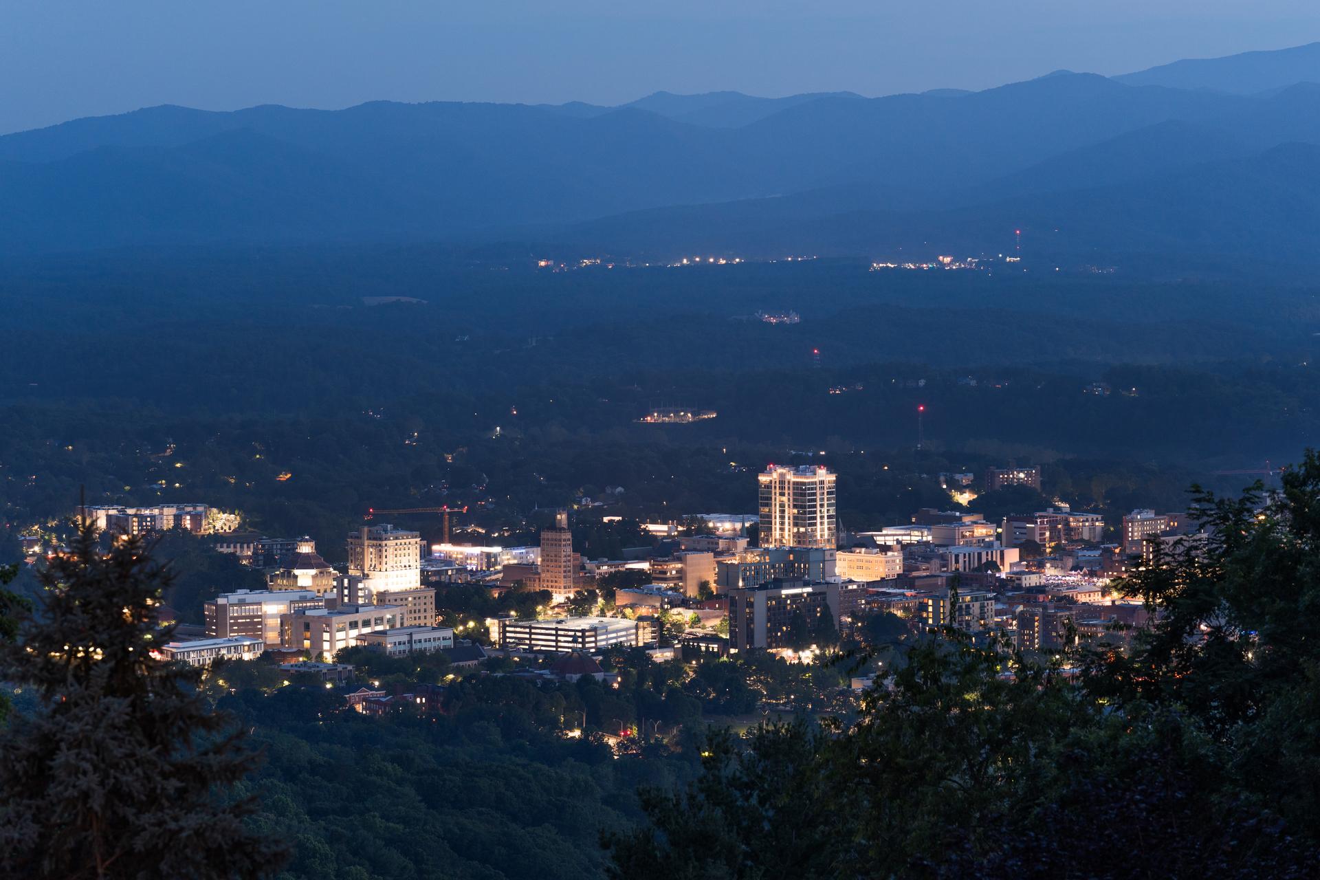Downtown Asheville lit up at dusk from the hills above the city
