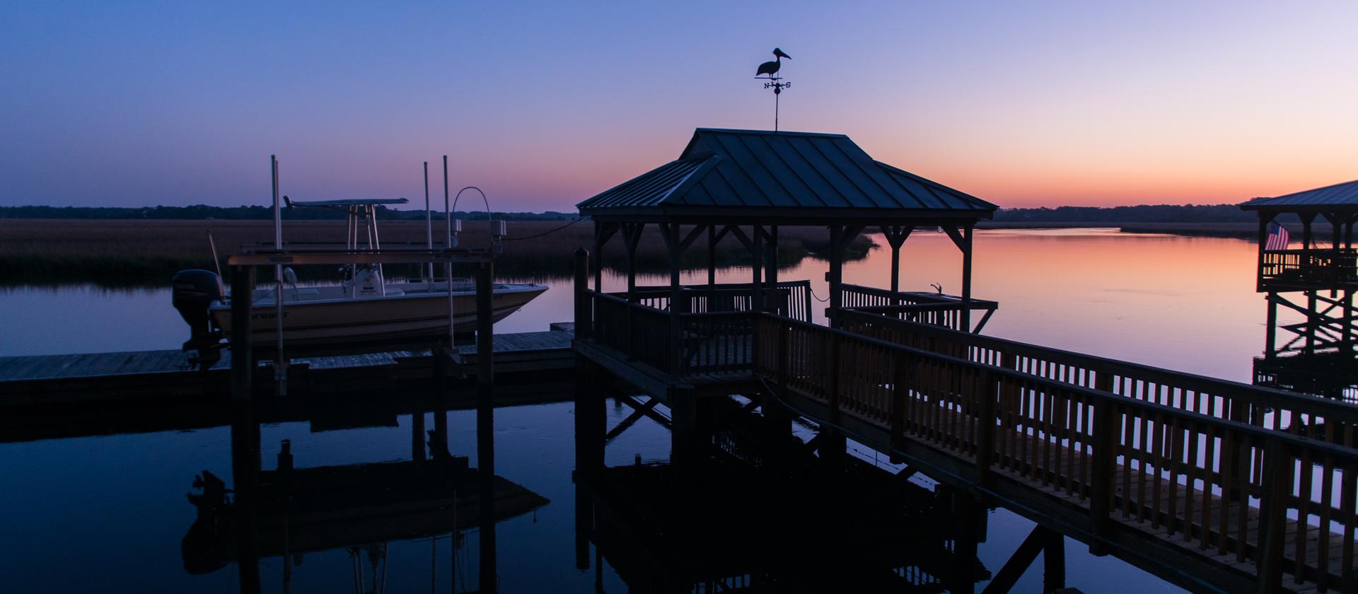 A covered dock and boat lift on a Charleston tidal creek at sunrise