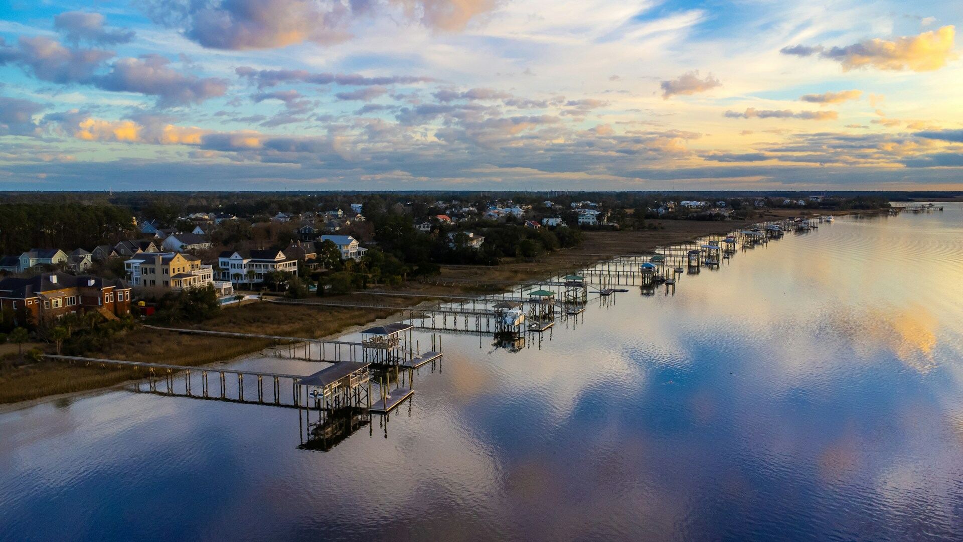 A dock and its reflection across still marsh water at dusk