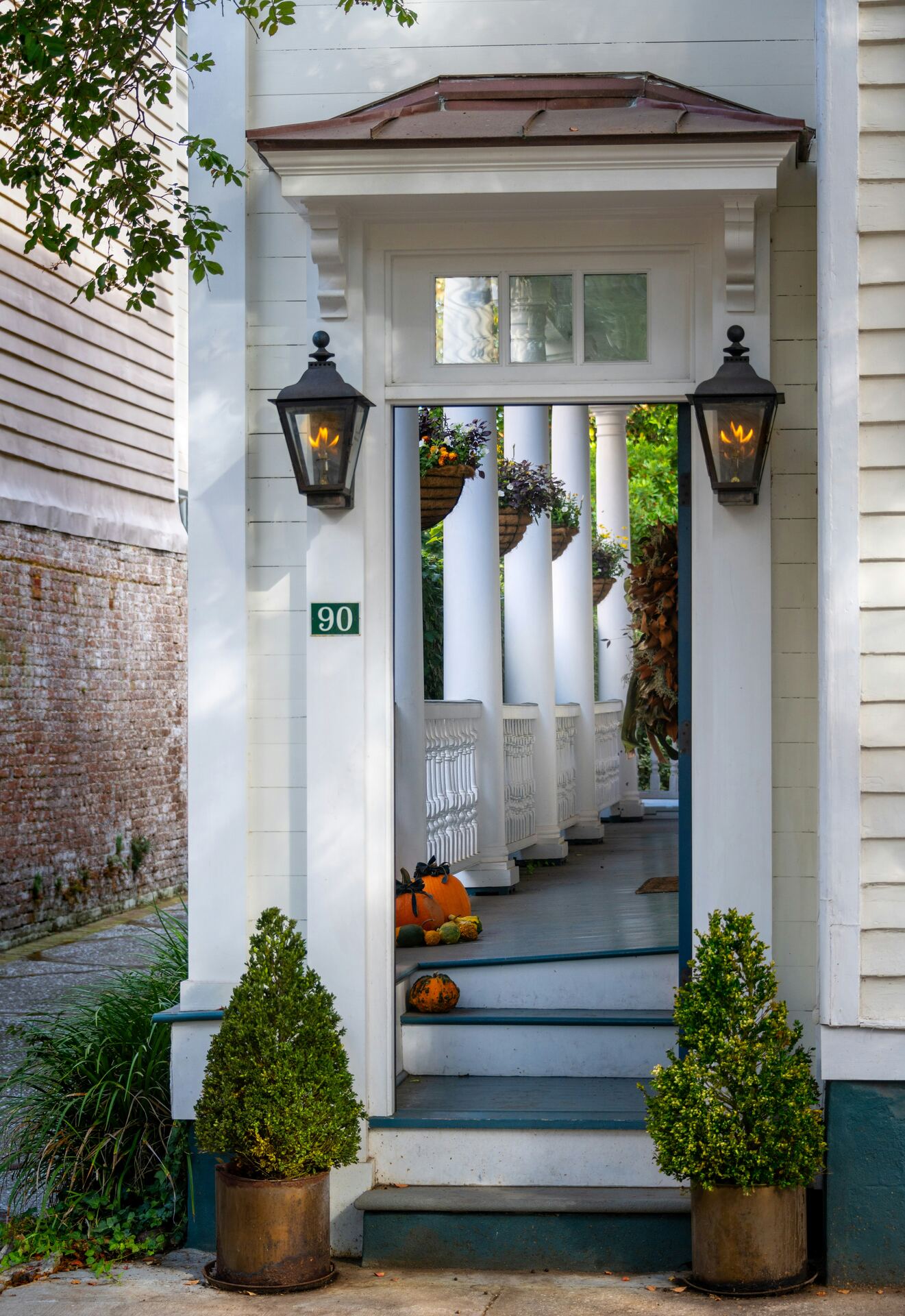 A Lowcountry piazza, lanterns lit, columns running down the porch