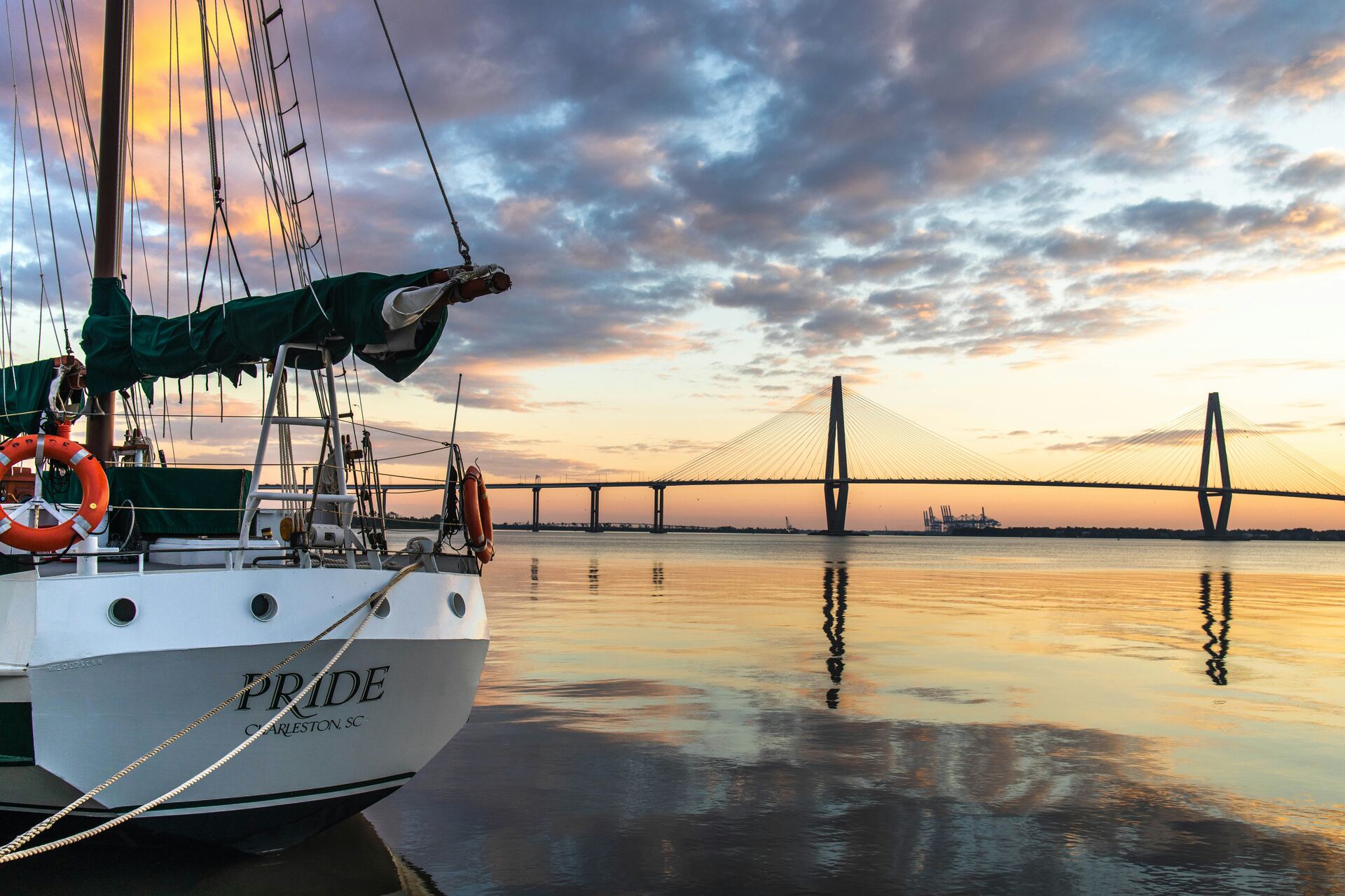 A schooner at anchor with the Ravenel Bridge beyond at first light