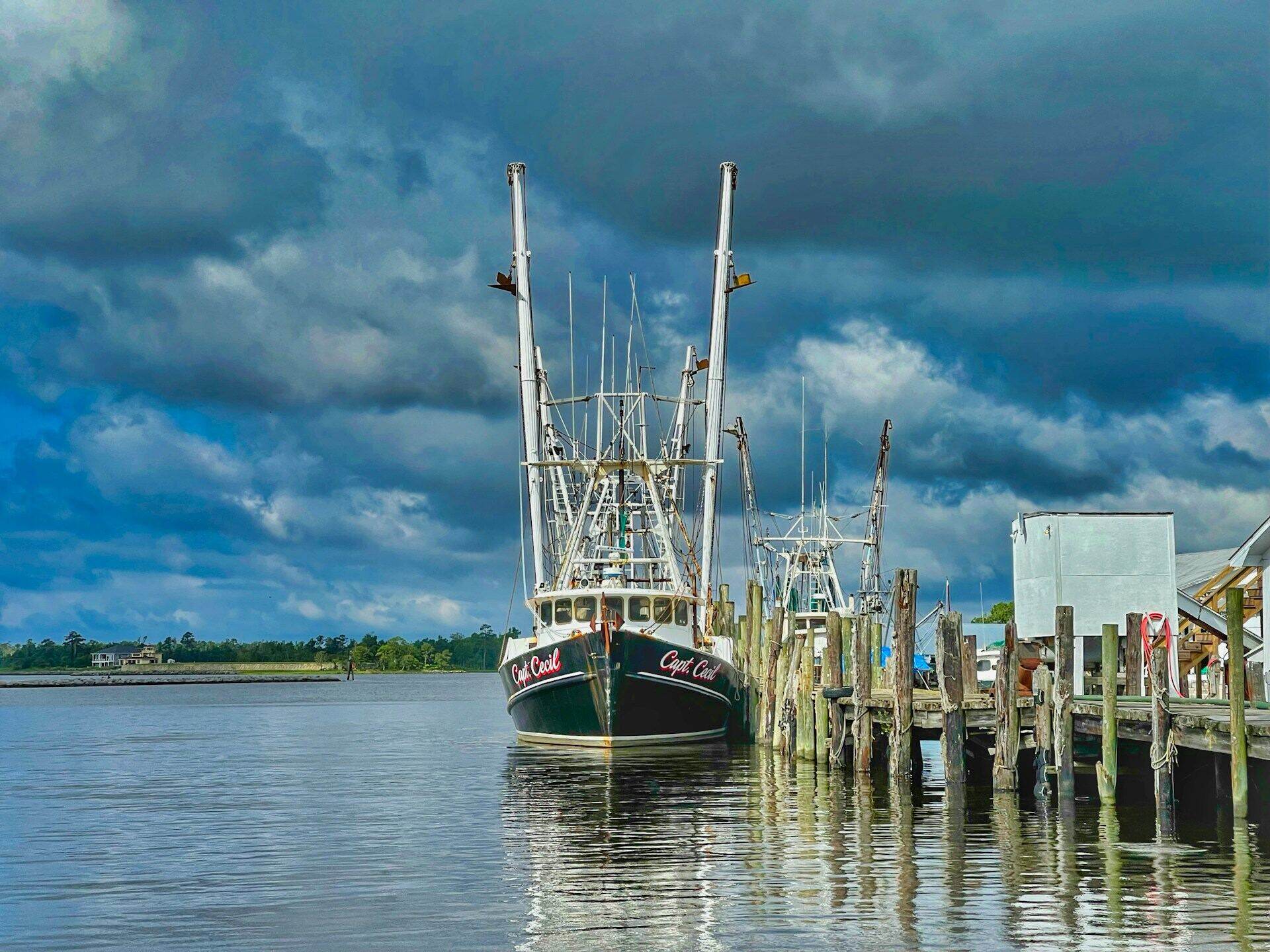 A shrimp boat tied up at a Lowcountry dock under a working sky
