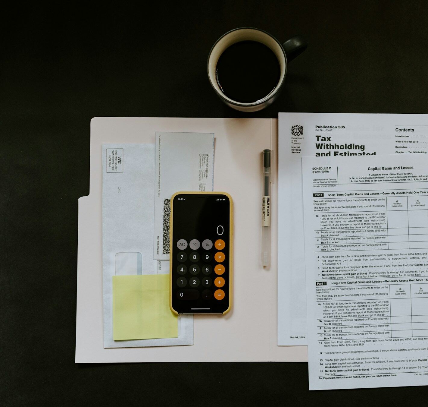 Tax withholding forms, a calculator and a cup of coffee on a desk