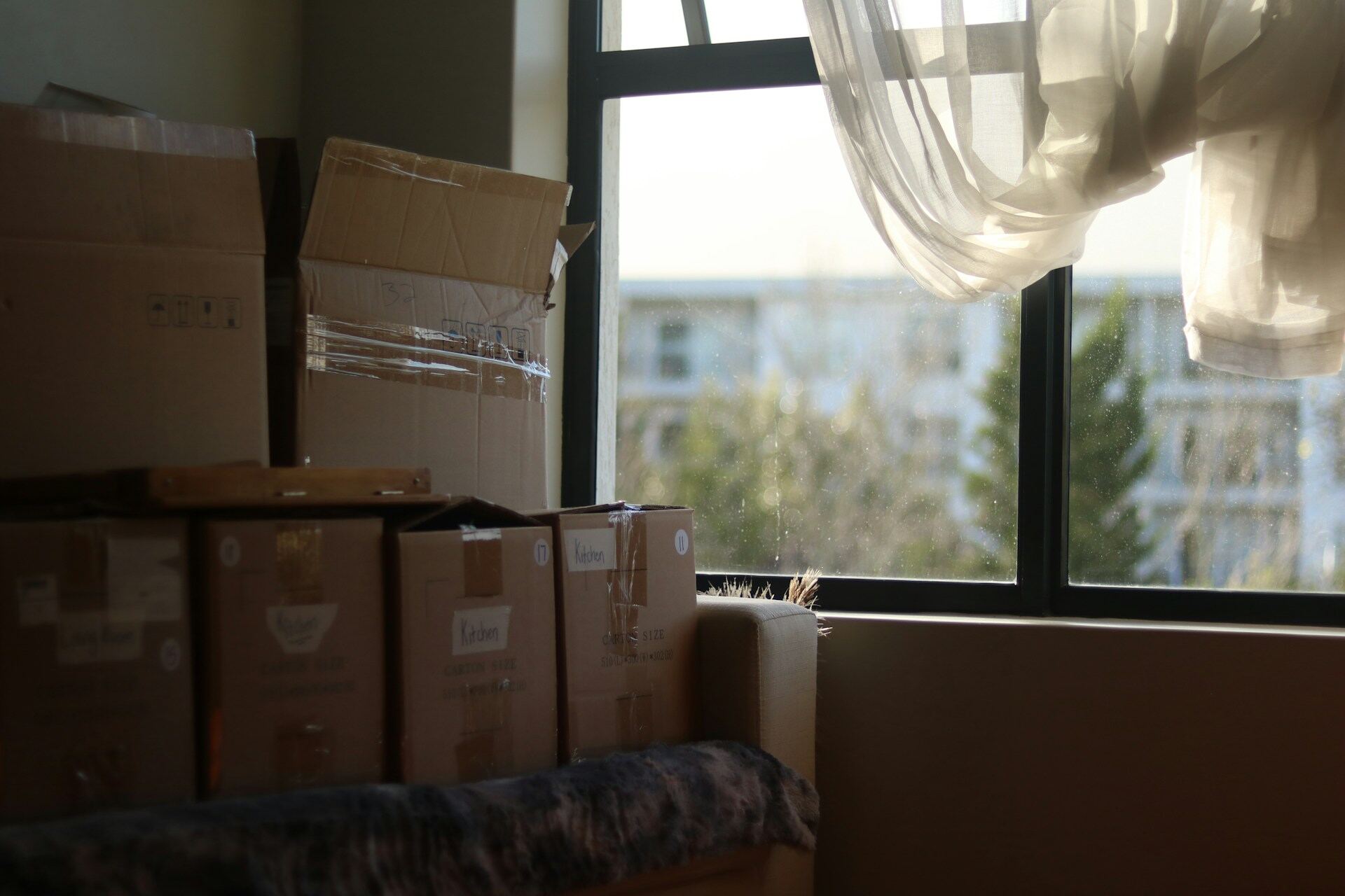 Stacked moving boxes in an empty room by a window