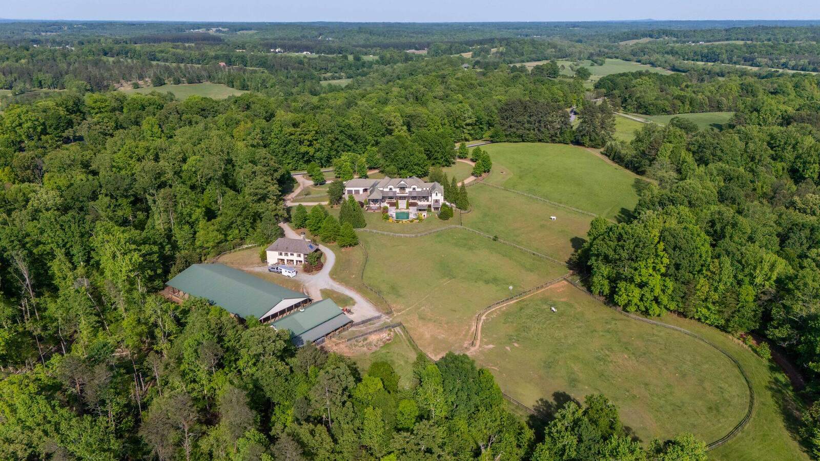 A Polk County horse farm from the air, pastures and barns among the treelines